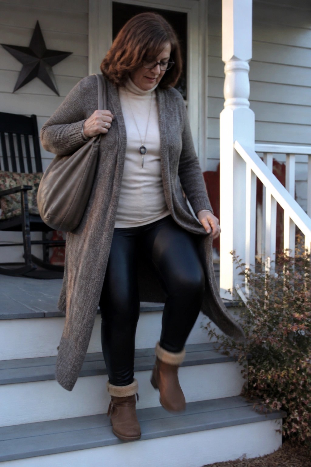 Woman in gray cardigan and black leggings descending porch steps with brown bag