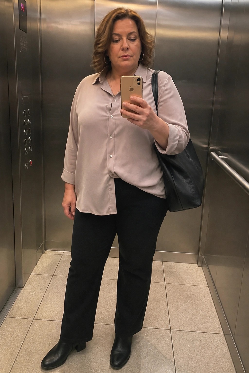 Woman in beige blouse and black pants taking selfie in elevator